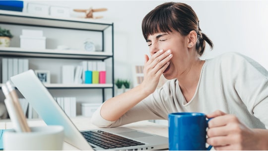 Девушка зевает перед ноутбуком